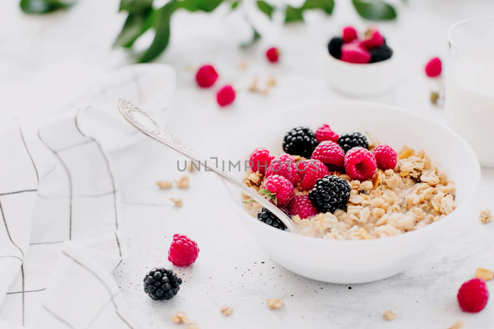 Morning healthy breakfast, white bowl full with granola, muesli, raspberry, blackberry on gray concrete table. Healthy eating, eco, bio food concept. Fresh tasty meal on grey background. Quality photo