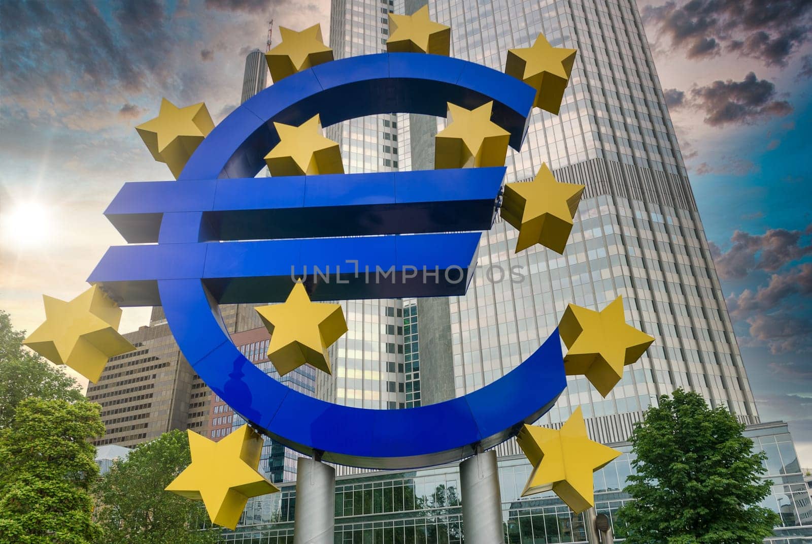 Euro sign at EZB Frankfurt downtown, sunset with flares, view from low angle, Germany