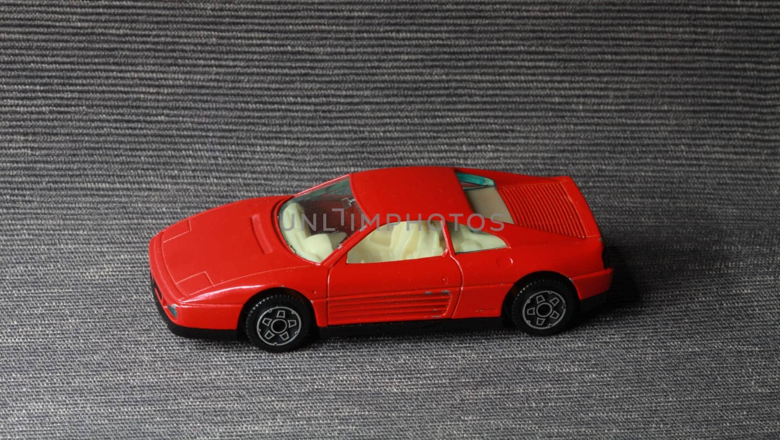small red toy car on a gray background still life