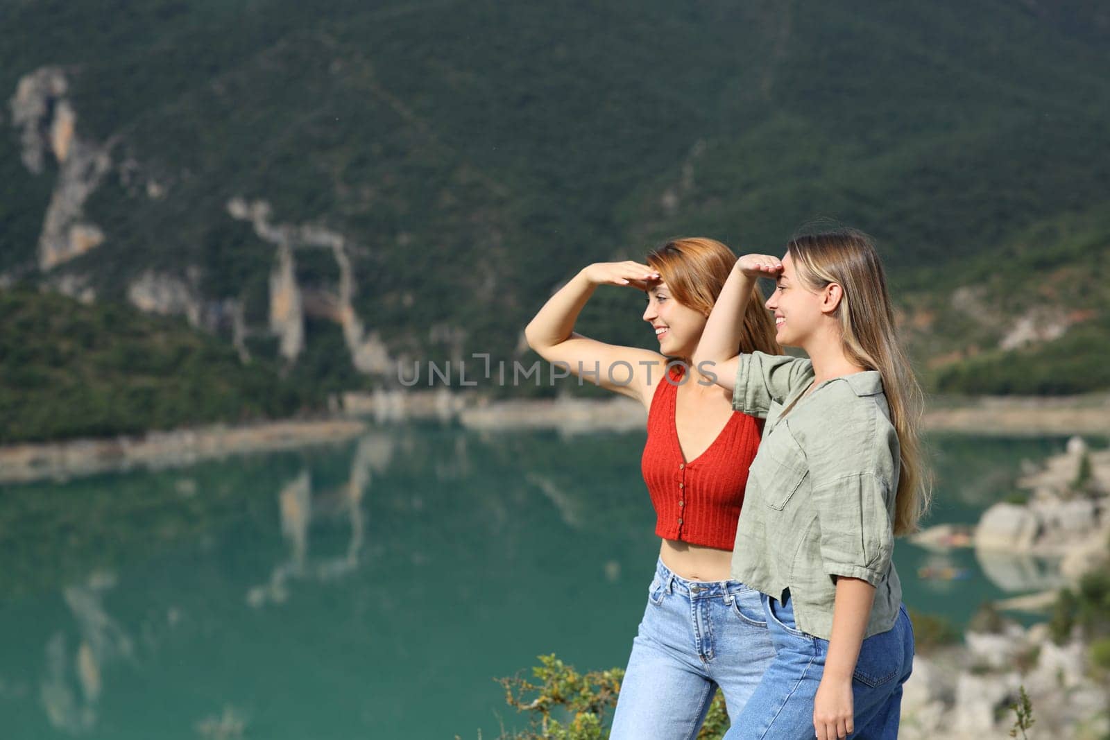 Two friends looking protecting from sun in the mountain on summer vacation