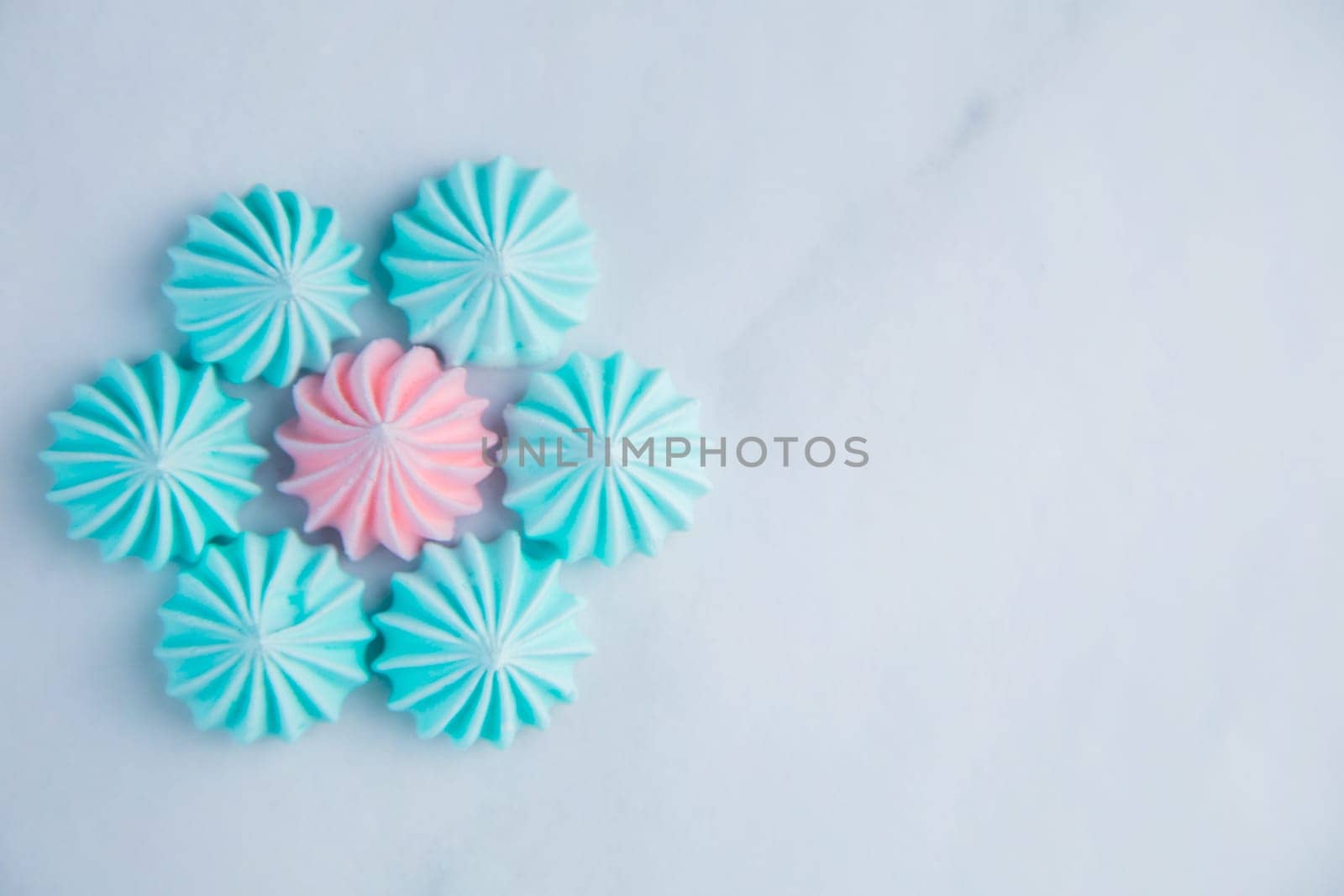 A flower with turquoise petals and a pink core made of meringue lies on a light marble background with a place for text. High quality photo