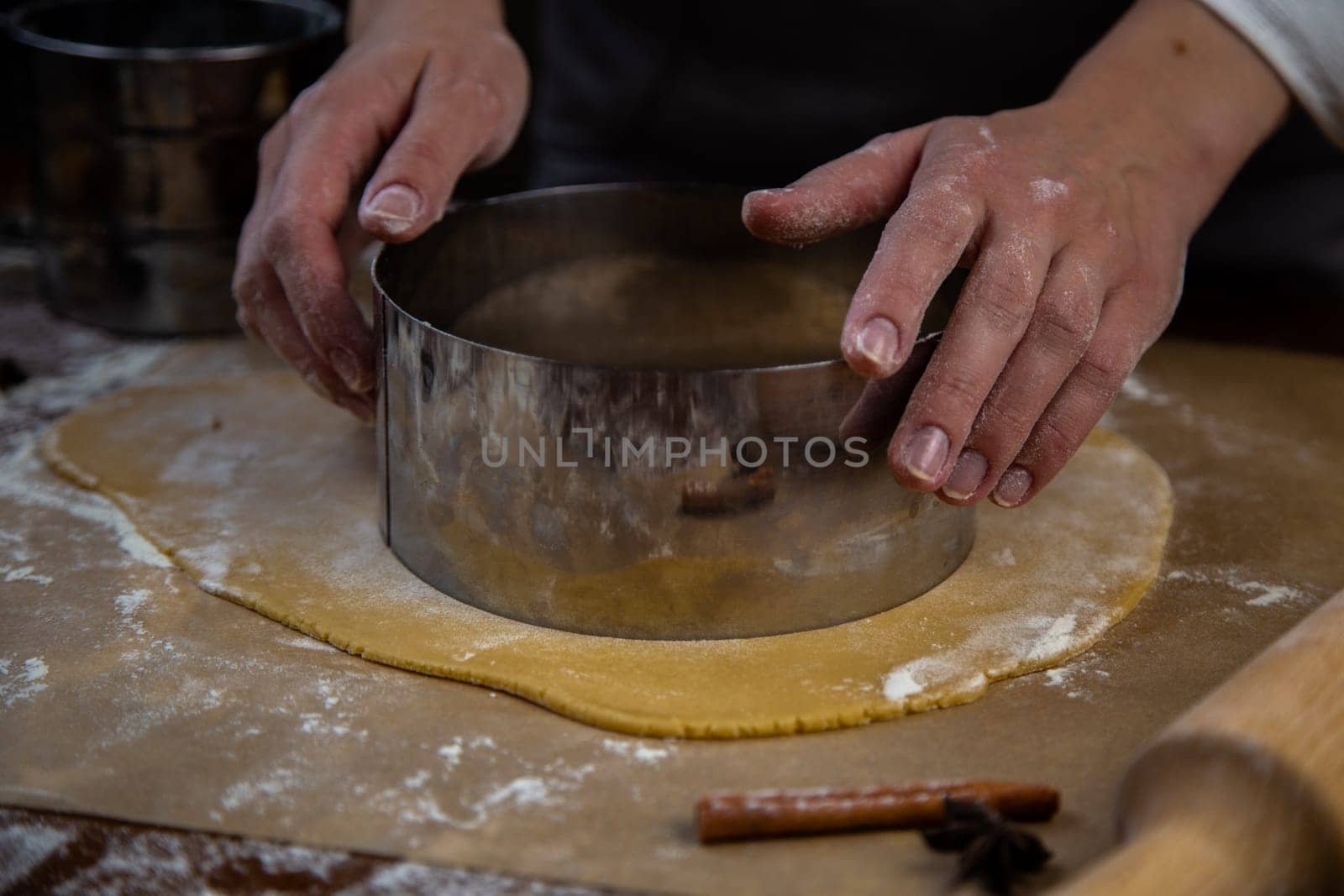 The rolled out layer of dough lies on baking paper, a cake cake is cut out of it with a metal cutter. High quality photo
