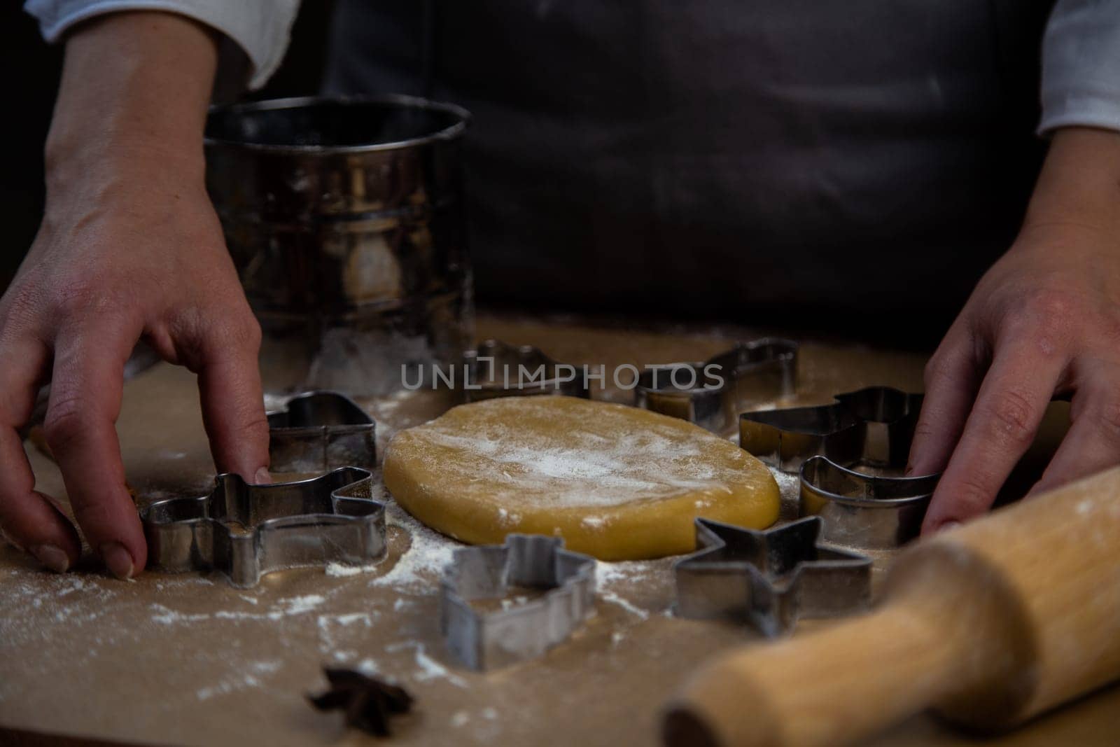 The rolled dough in the form of a circle lies on baking parchment surrounded by cookie cutters. High quality photo