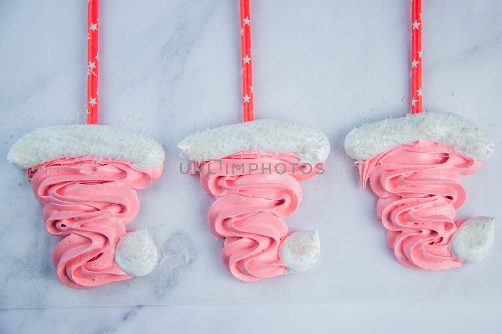 Santa Claus Christmas hats made of pink bizet on red sticks are lying on baking paper. High quality photo