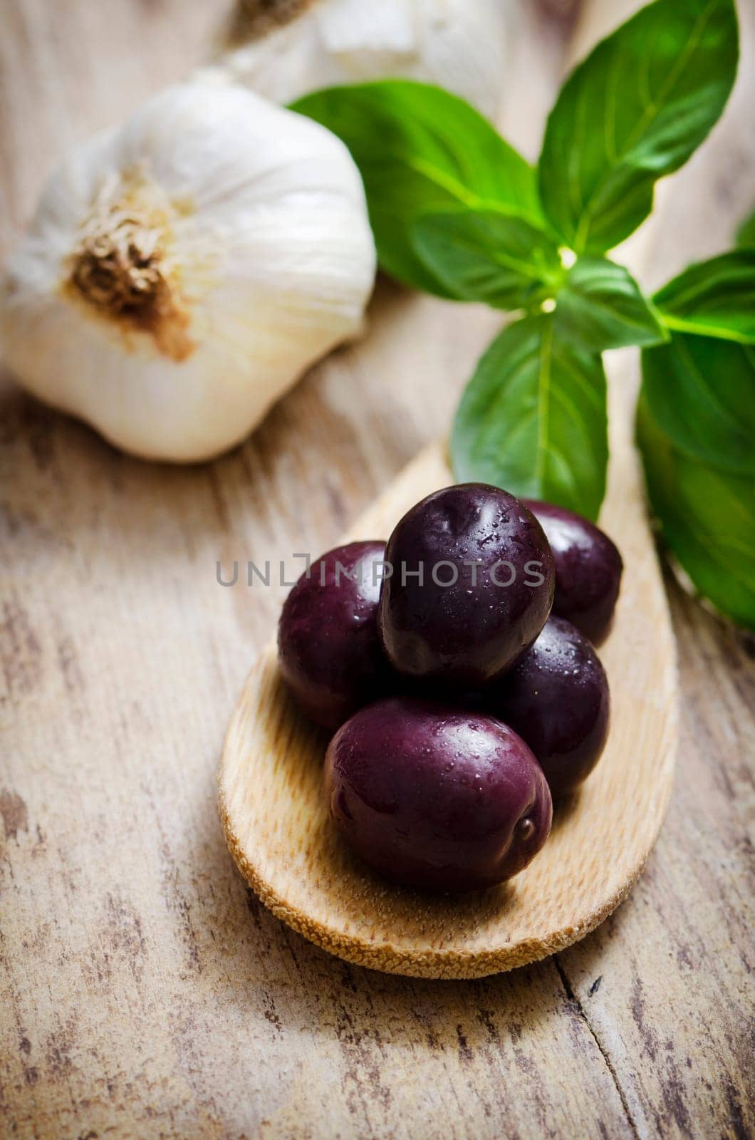 Black olives and basil on wooden table