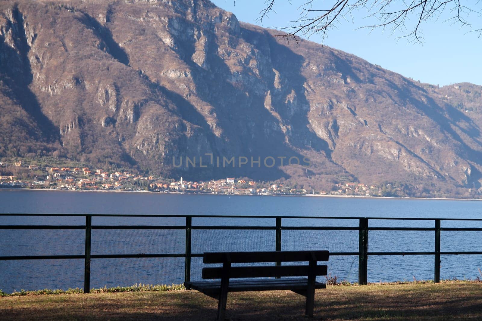 Close up of a brown bench looking at the lake and Alps on the shore of Lake Como in Italy