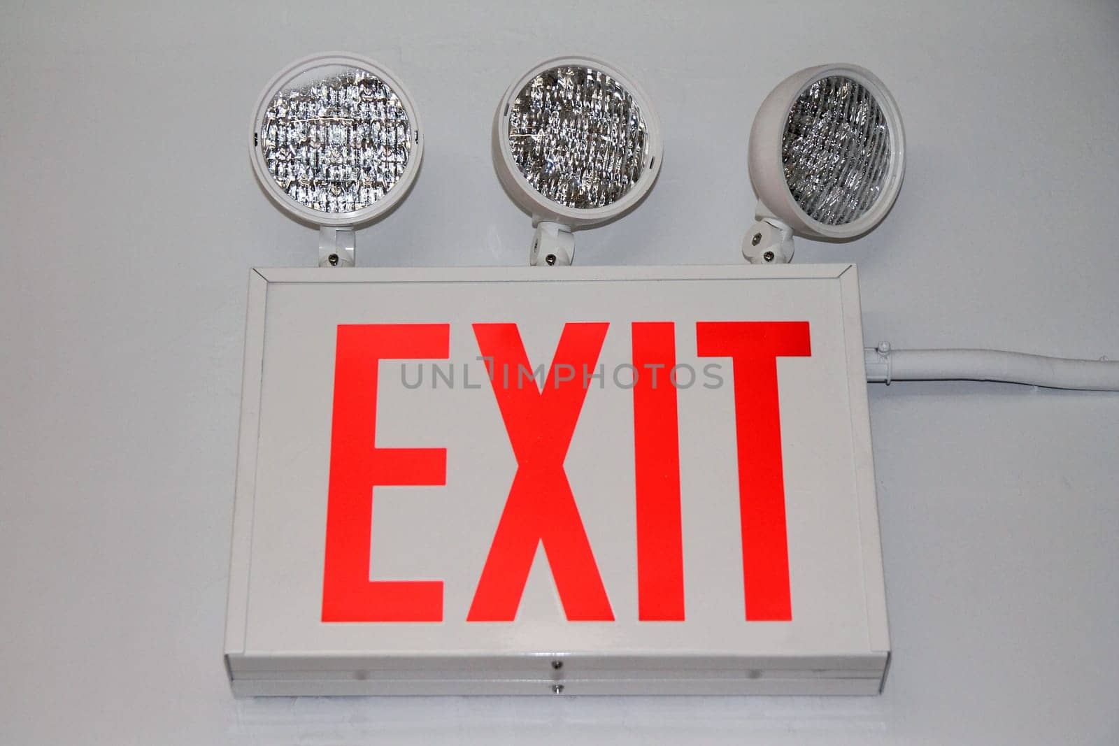 The flashing red security exit sign with three powerful lights on the exit of a building