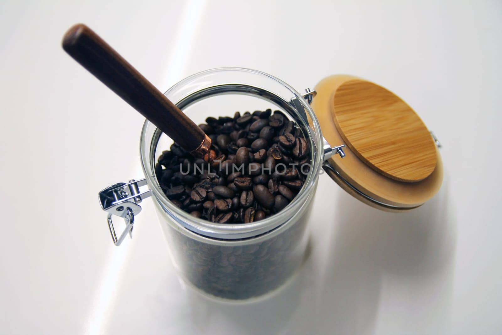 Close up of a isolated glass and wood coffee jar with a copper and wood spoon with its lock