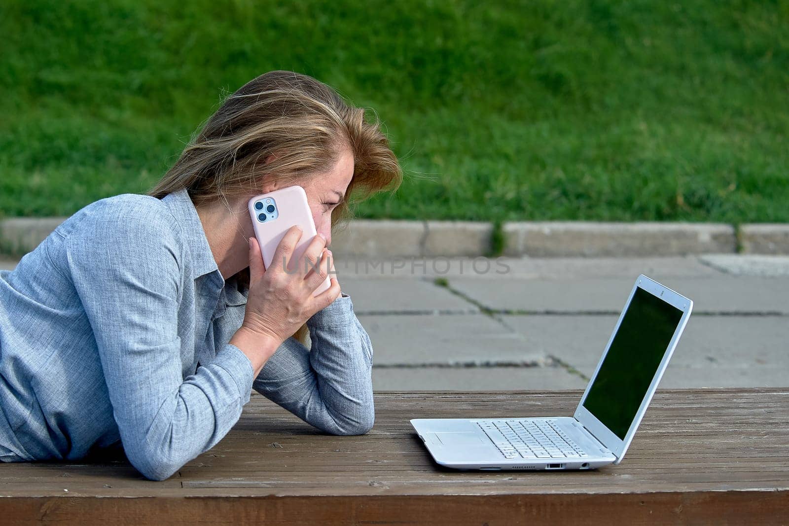 A woman with a laptop sits on a wooden platform, works online. High quality photo