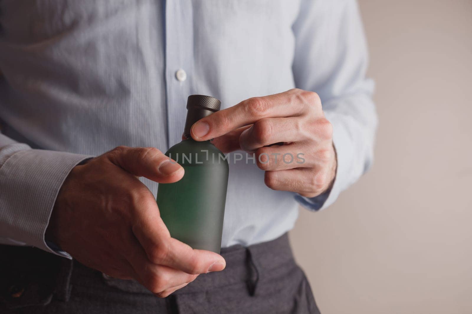 Man in formal wear holding perfume bottle, closeup. Space for text