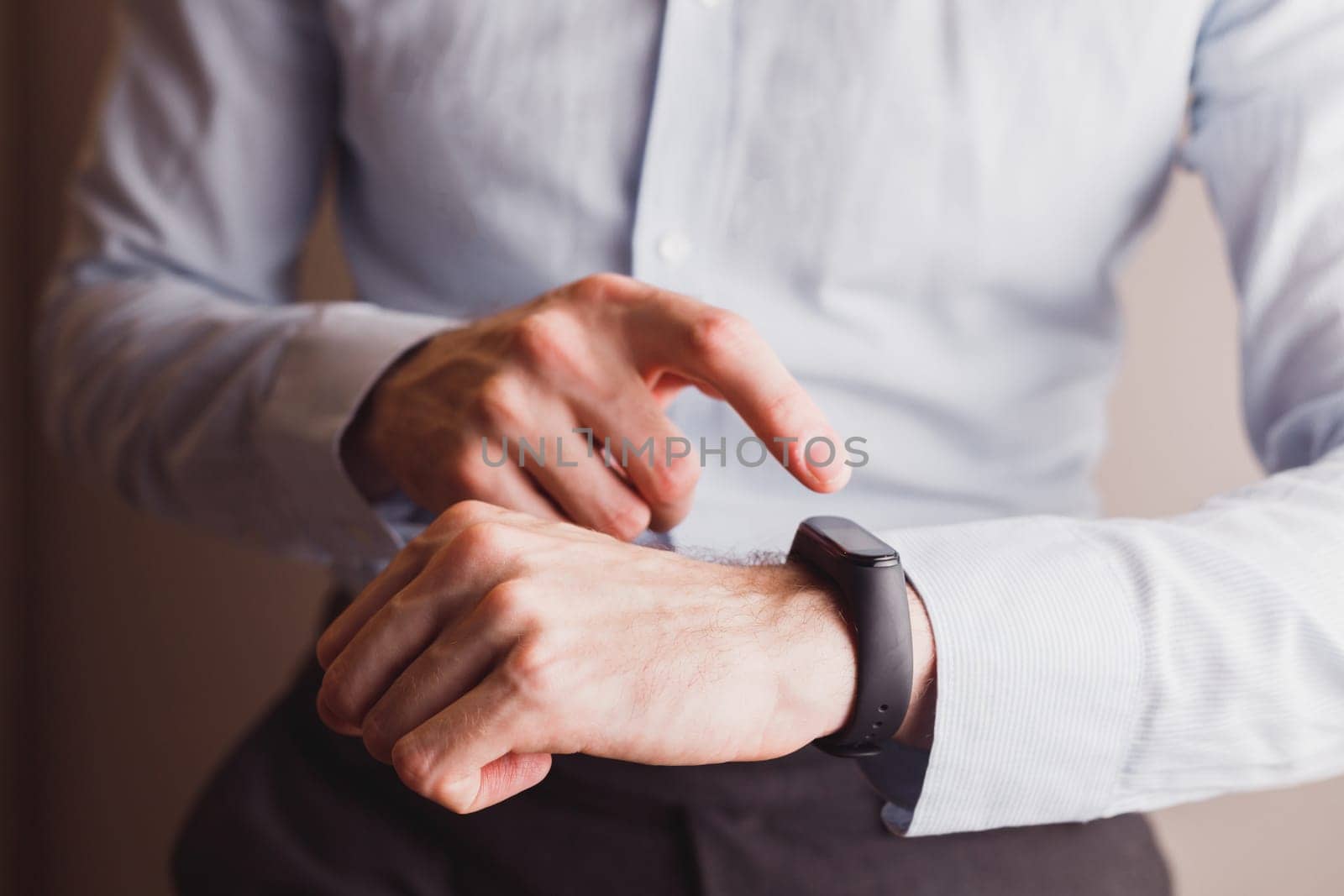 Office man in blue shirt, using smart watch or bracelet. Touching screen to set Technology lifestyle