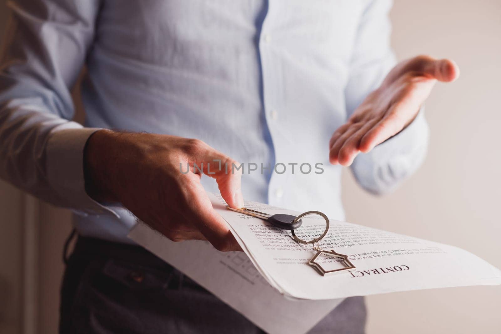 Manager offers keys to house holding contract in other hand. Rental and buying a property