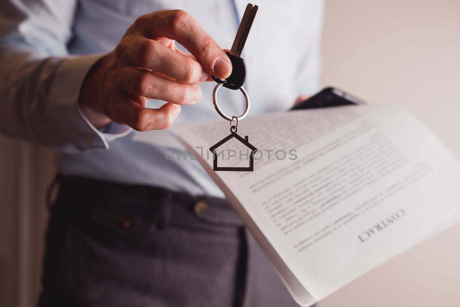 Manager offers keys to house holding contract in other hand. Rental and buying a property