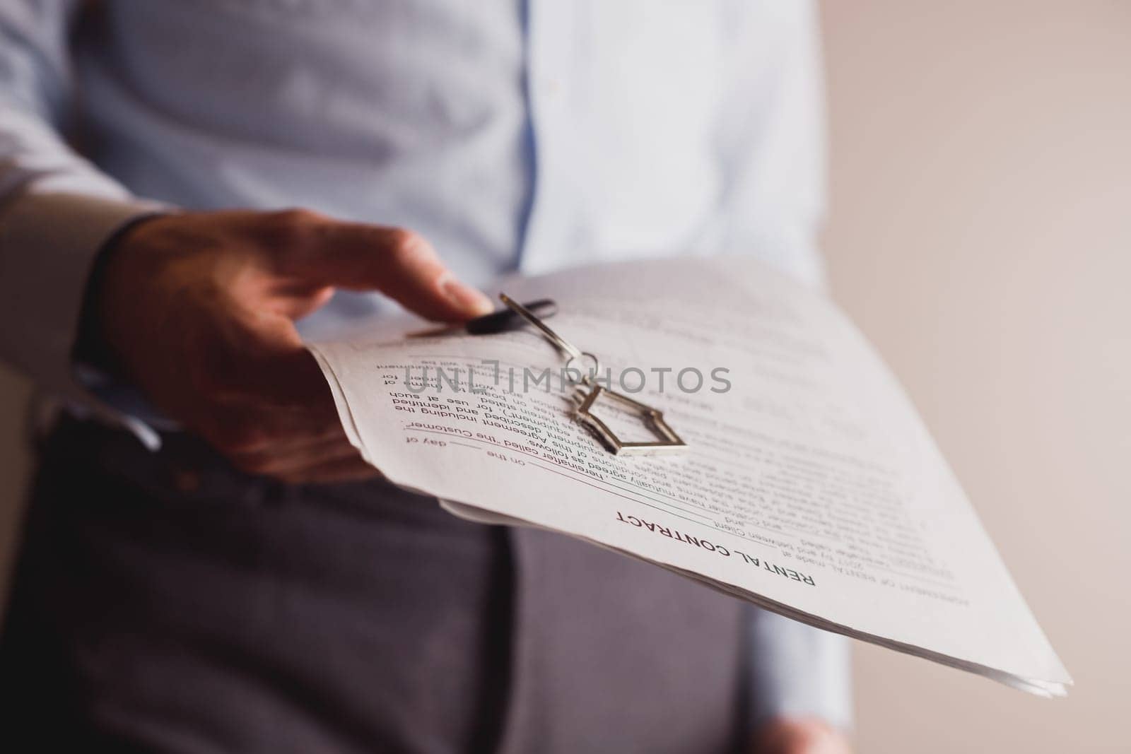 Manager offers keys to house holding contract in other hand. Rental and buying a property