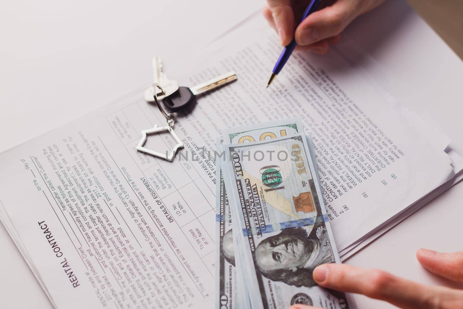 Man signing real estate contract, making a deal with cash dollar money and home keys. Buying or rent