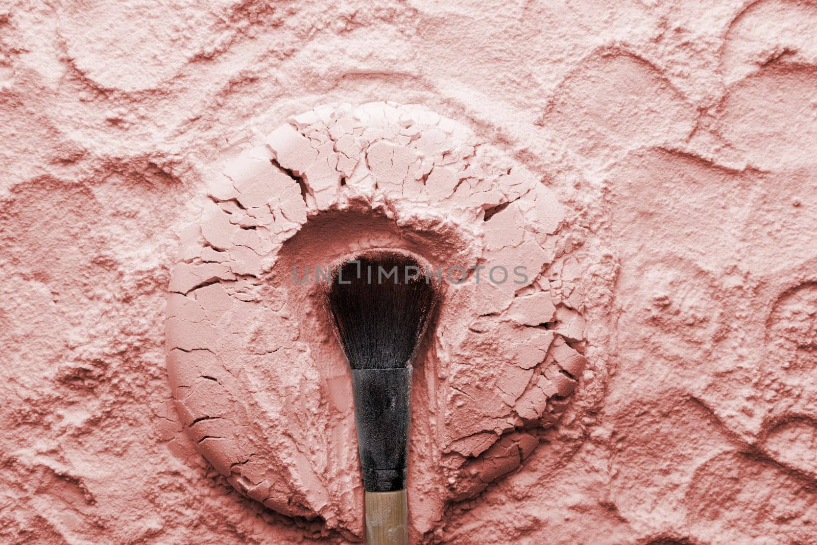 Makeup brushes on pink cosmetic powder background. Flat lay, top view.