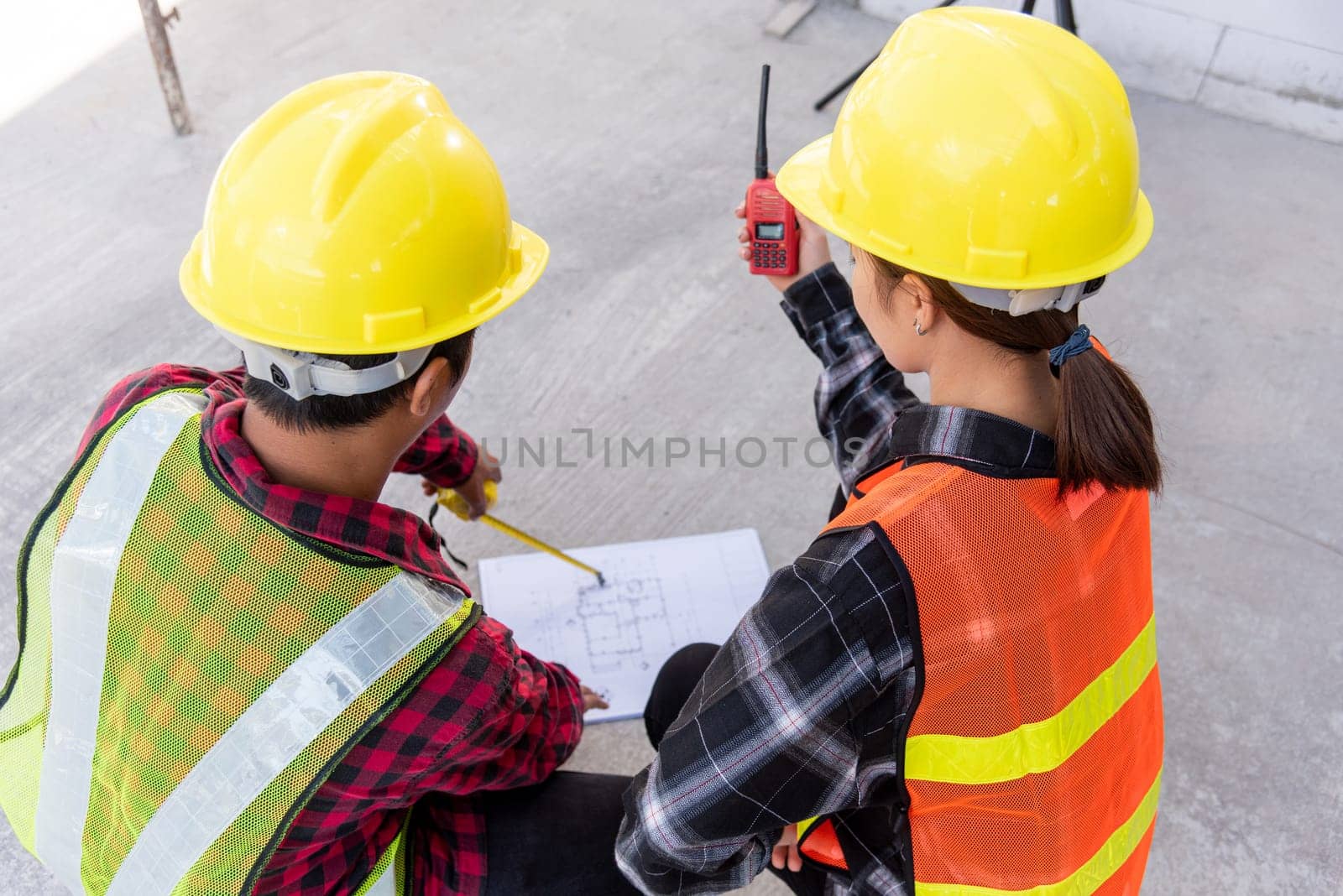 Architect and client discuss help create plan with blueprint of the building at construction site floor. Asian engineer foreman worker man and woman meeting talking on drawing paper project, top view