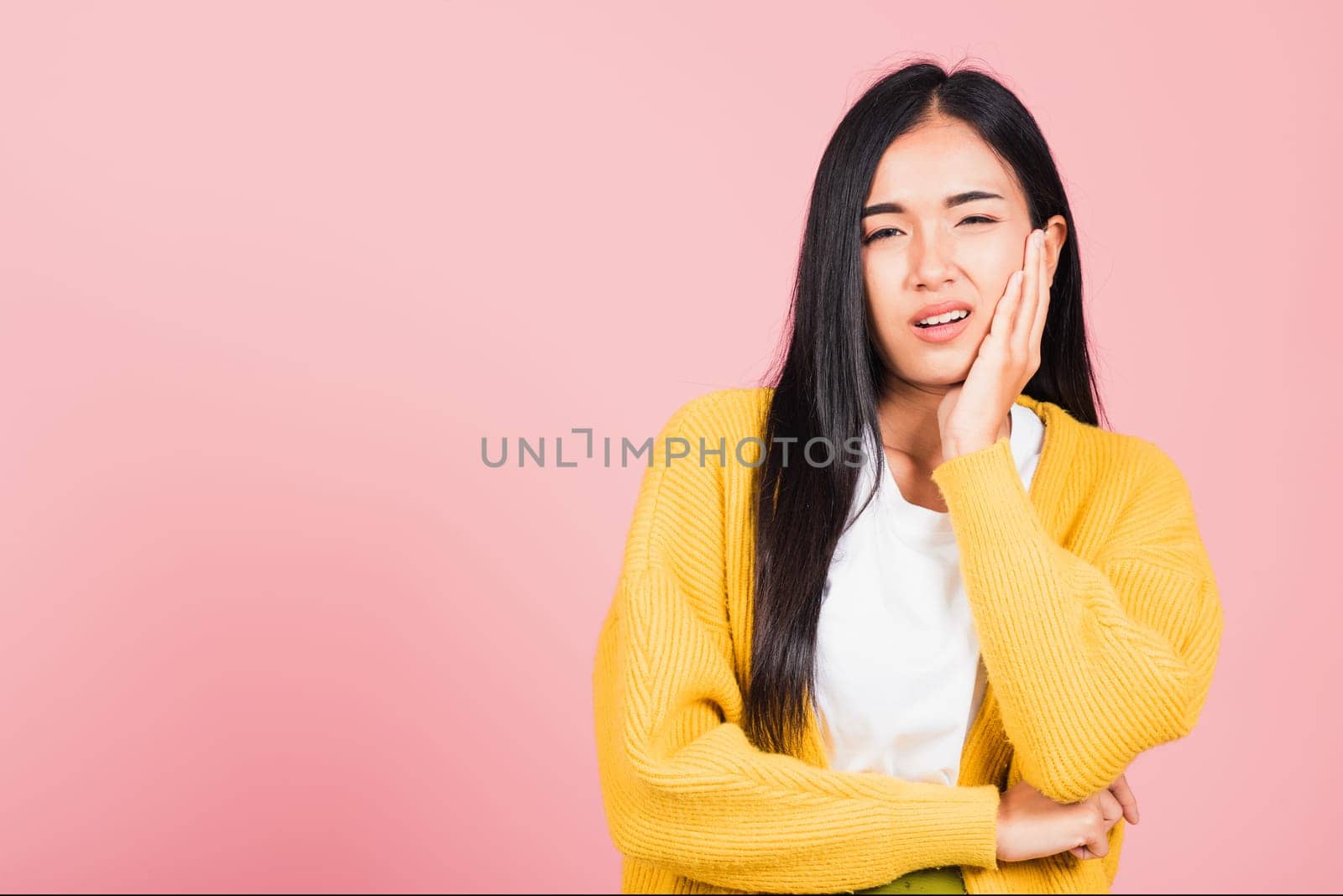 Portrait of Asian beautiful young woman suffering from toothache, female terrible strong teeth pain problem pressing hand to chin, studio shot isolated on pink background, Dental health care concept