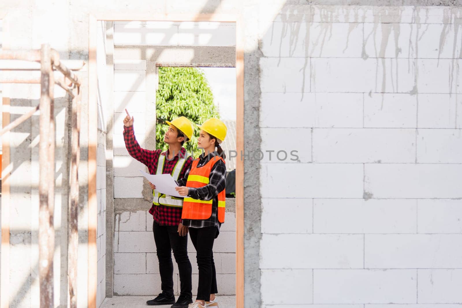 Architect and client discussing the plan with blueprint of the building at construction site. Asian engineer foreman worker man and woman working talking and checking on draw paper to checking project
