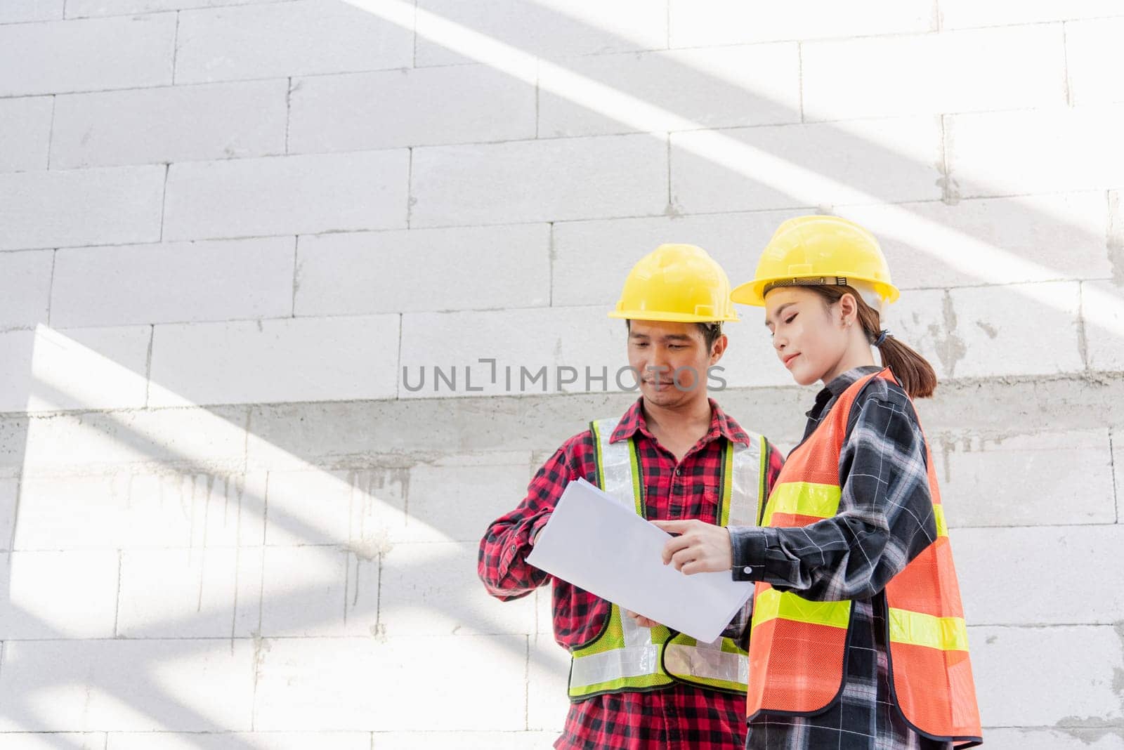 Architect and client discussing the plan with blueprint of the building at construction site. Asian engineer foreman worker man and woman working talking and checking on draw paper to checking project