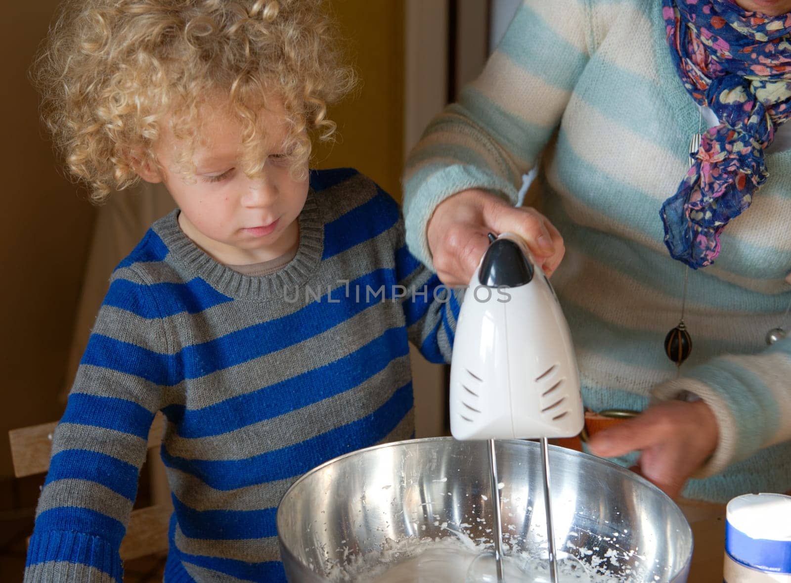 Young child baking at home with a grandparent