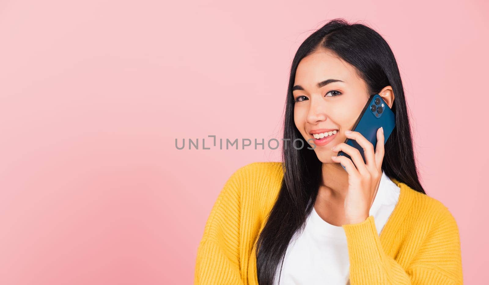 Portrait Asian happy beautiful young woman smile talking by smartphone looking to camera isolated, studio shot isolated on pink background, Thai female hold the phone to calling with copy space