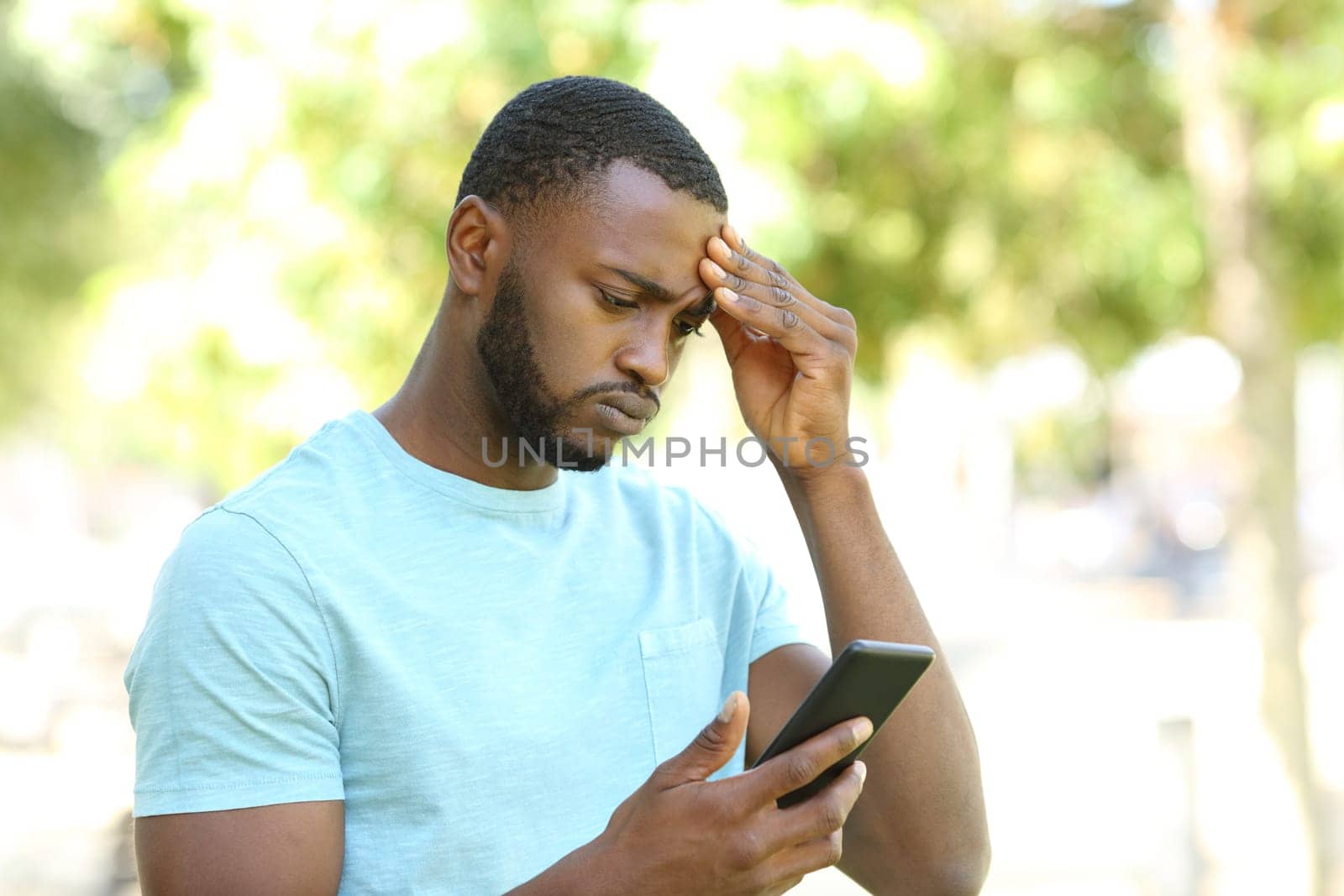 Concerned man with black skin checking phone