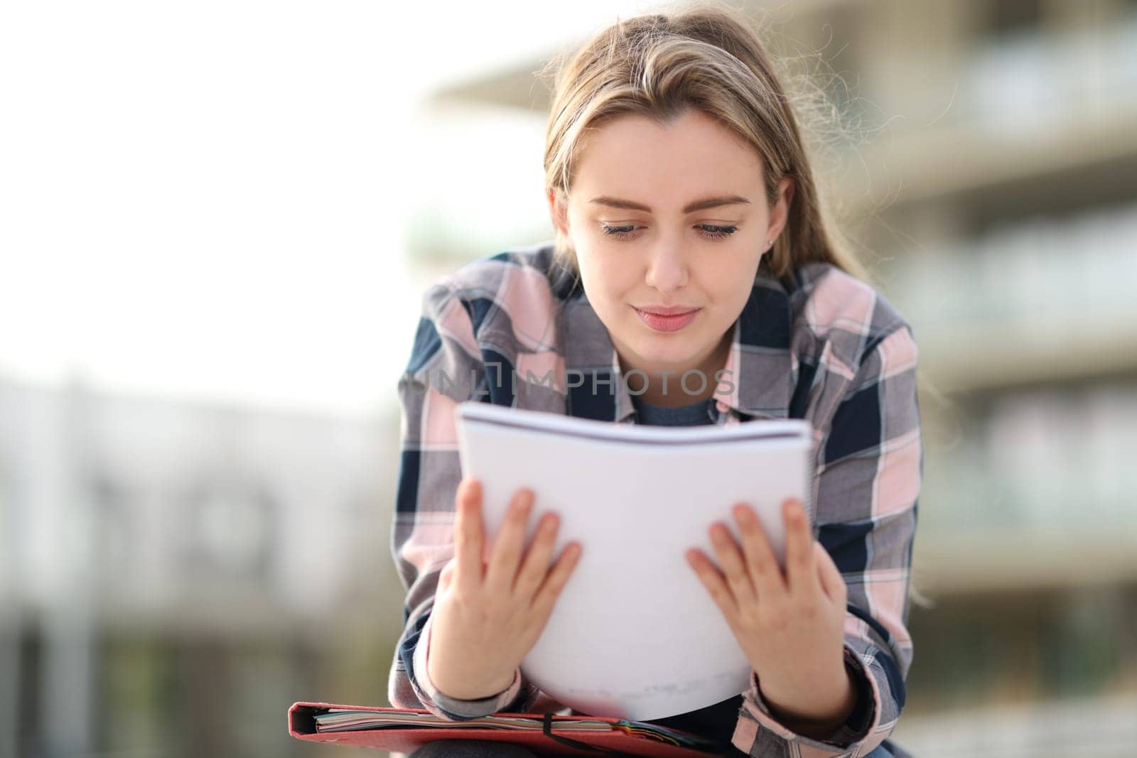 Student studying reading notes outdoors