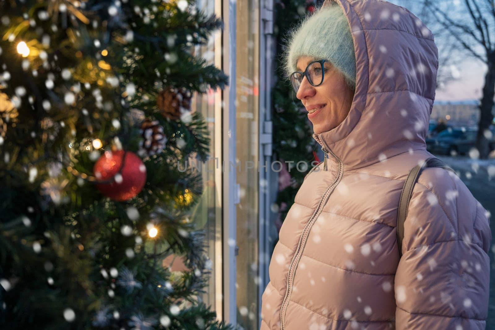 Pretty Woman near illuminated new year decorated window. Xmas holidays, or shopping on New Year or Christmas concept