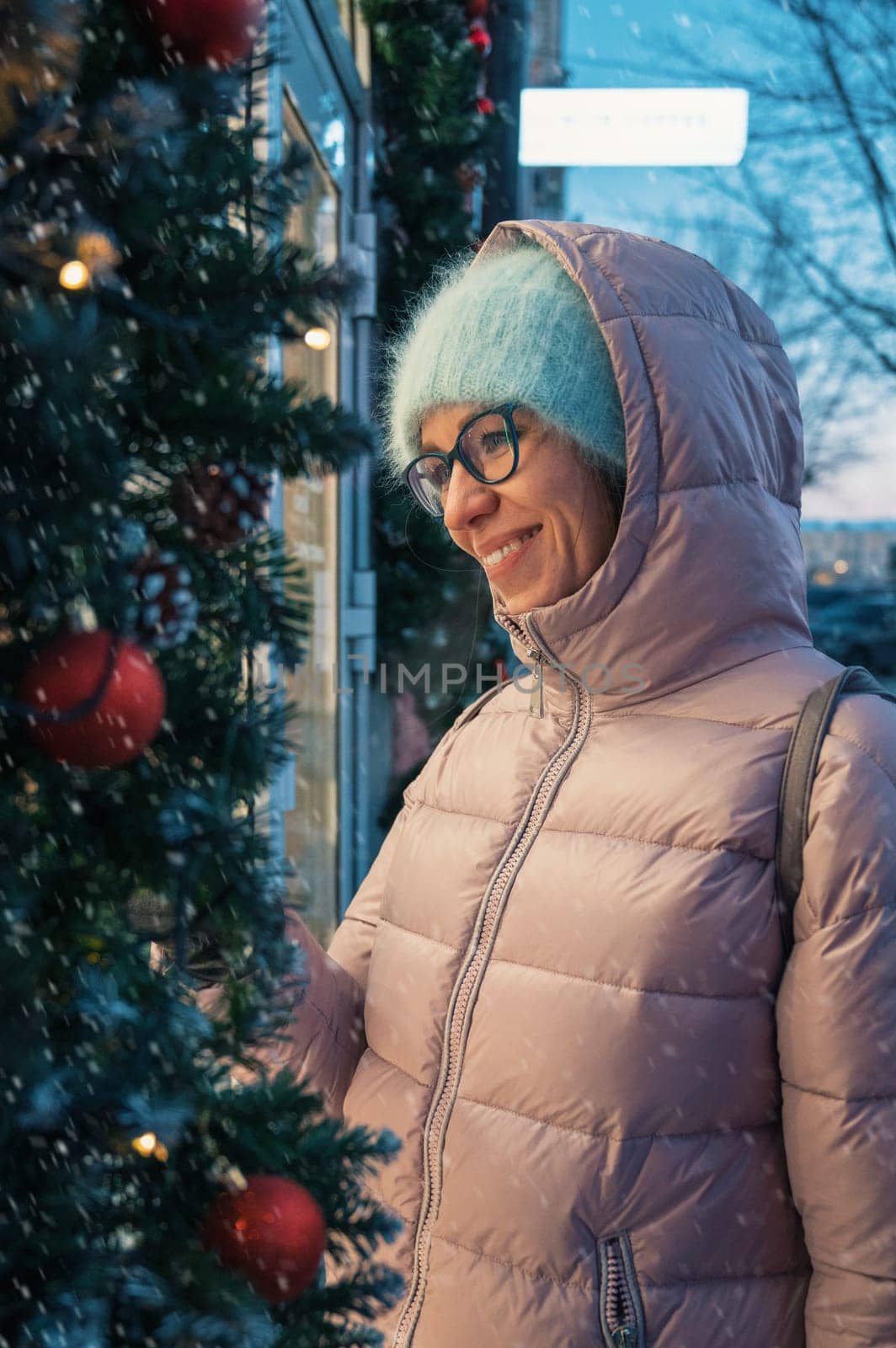 Pretty Woman near illuminated new year decorated window. Xmas holidays, or shopping on New Year or Christmas concept