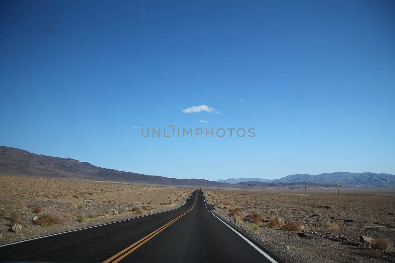 Straight road towards mountain range in horizon at Death Valley in California