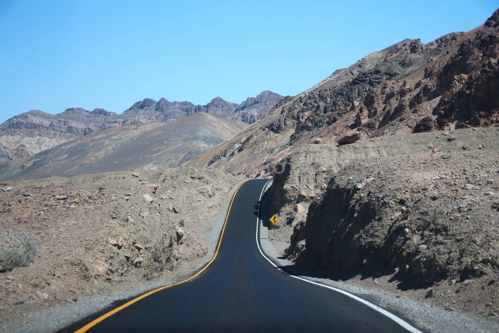 The dip in the black road on the rock formations of the desert