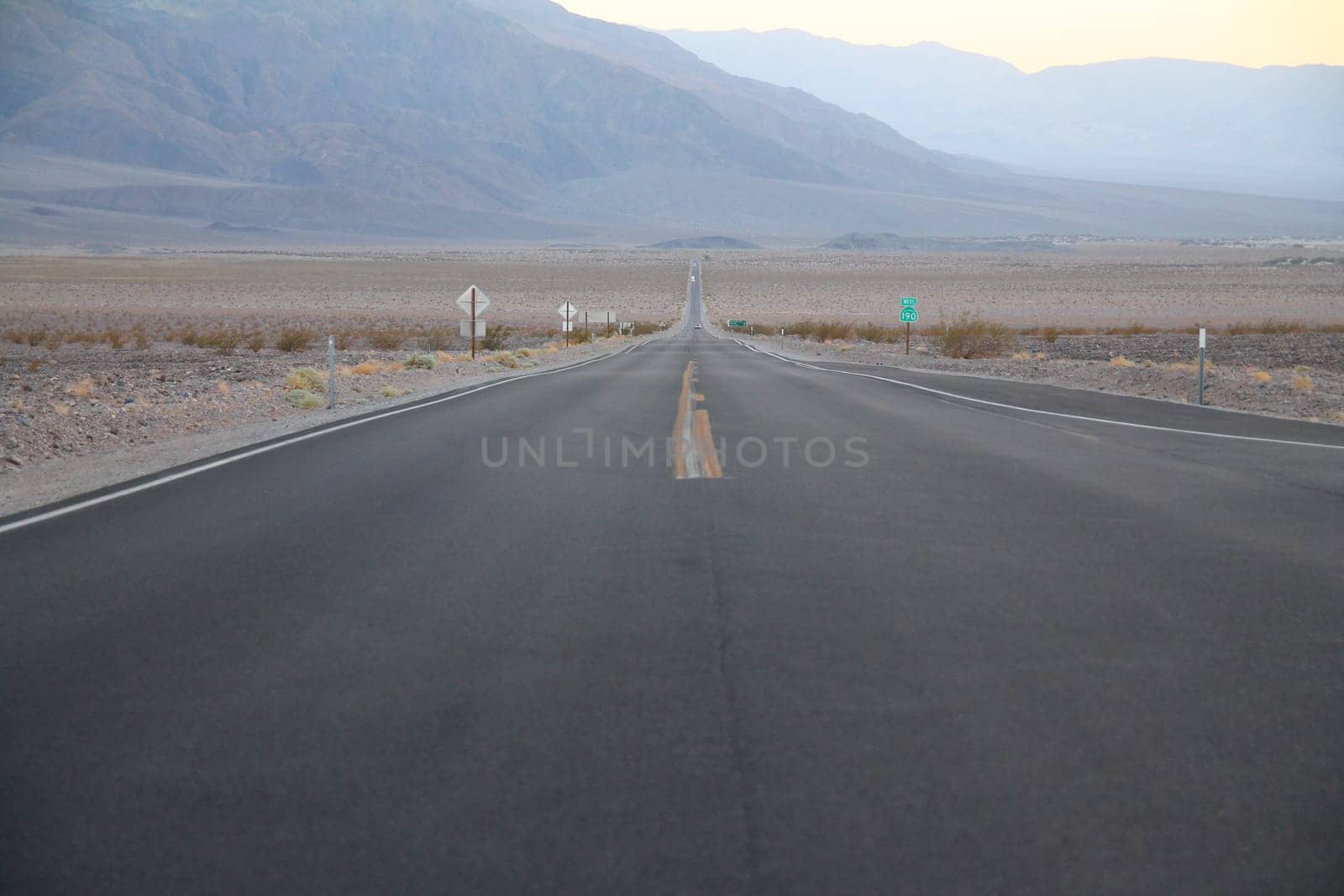 The never ending road during the dusk of a sunset in the Death Valley desert in California