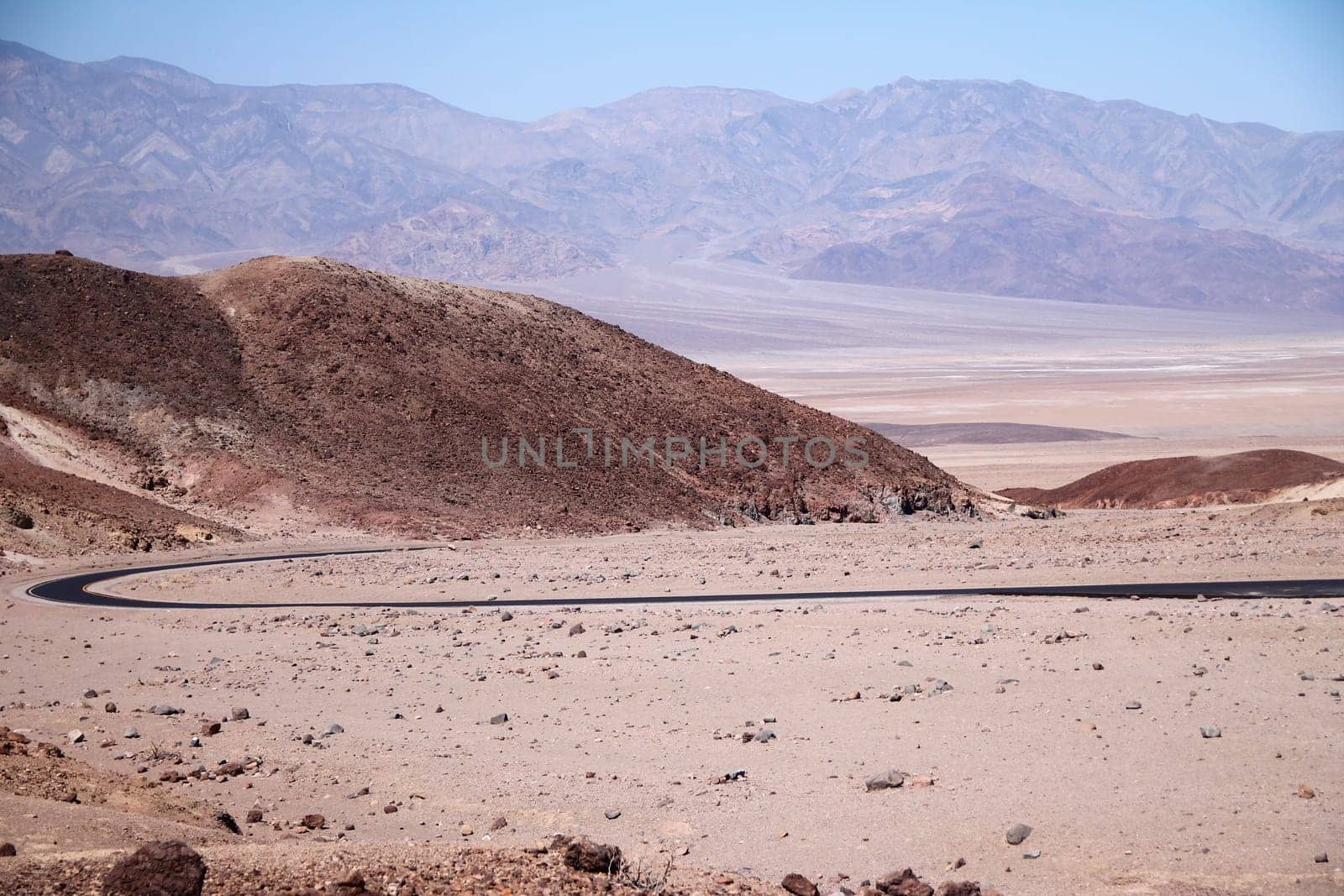 Boomerang bow asphalt street in the beige colors of the desert of Death Valley in California