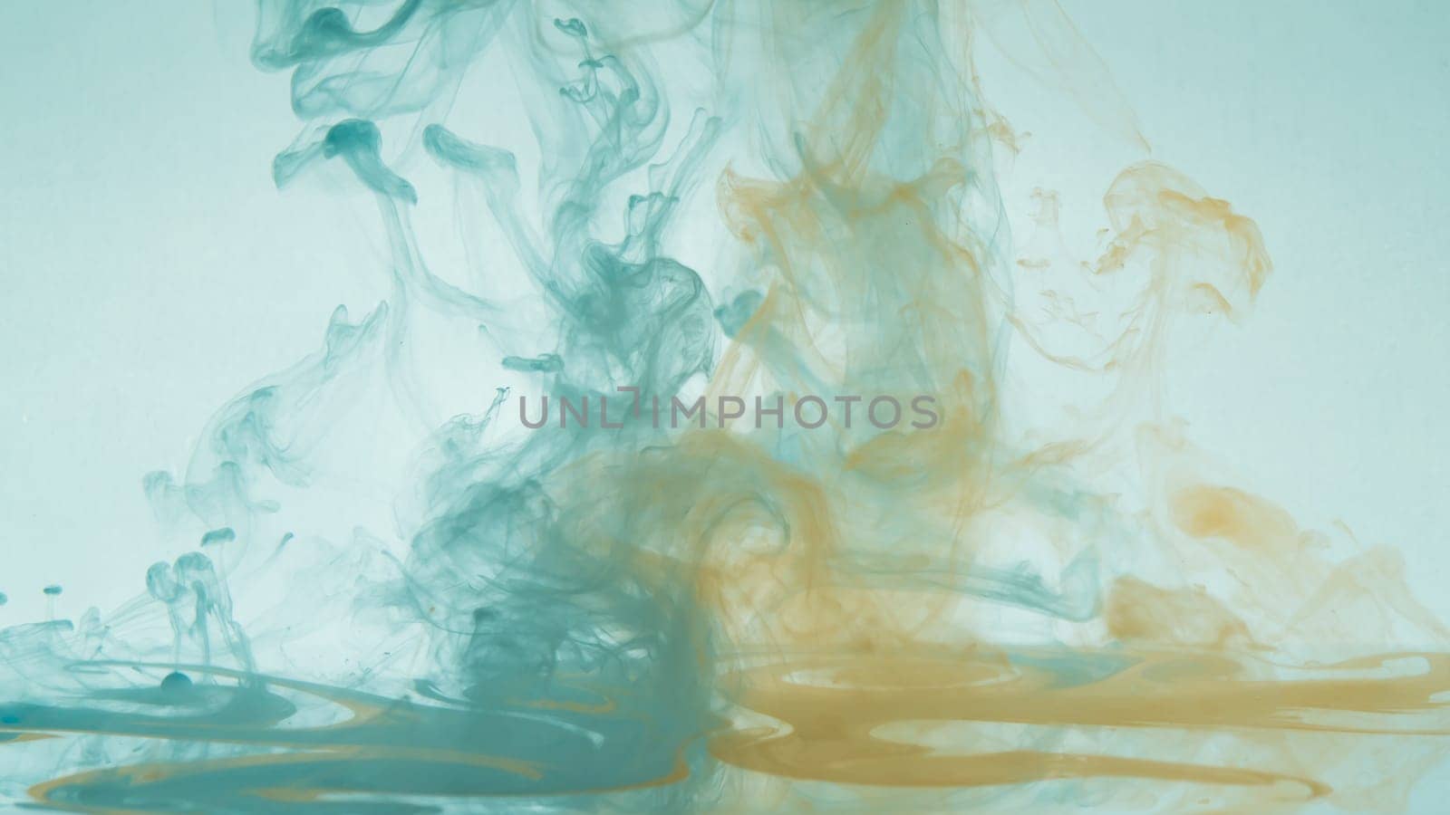Paint in the water. ink in fluid. abstract background. colorful splashes in liquid. yellow and blue colors