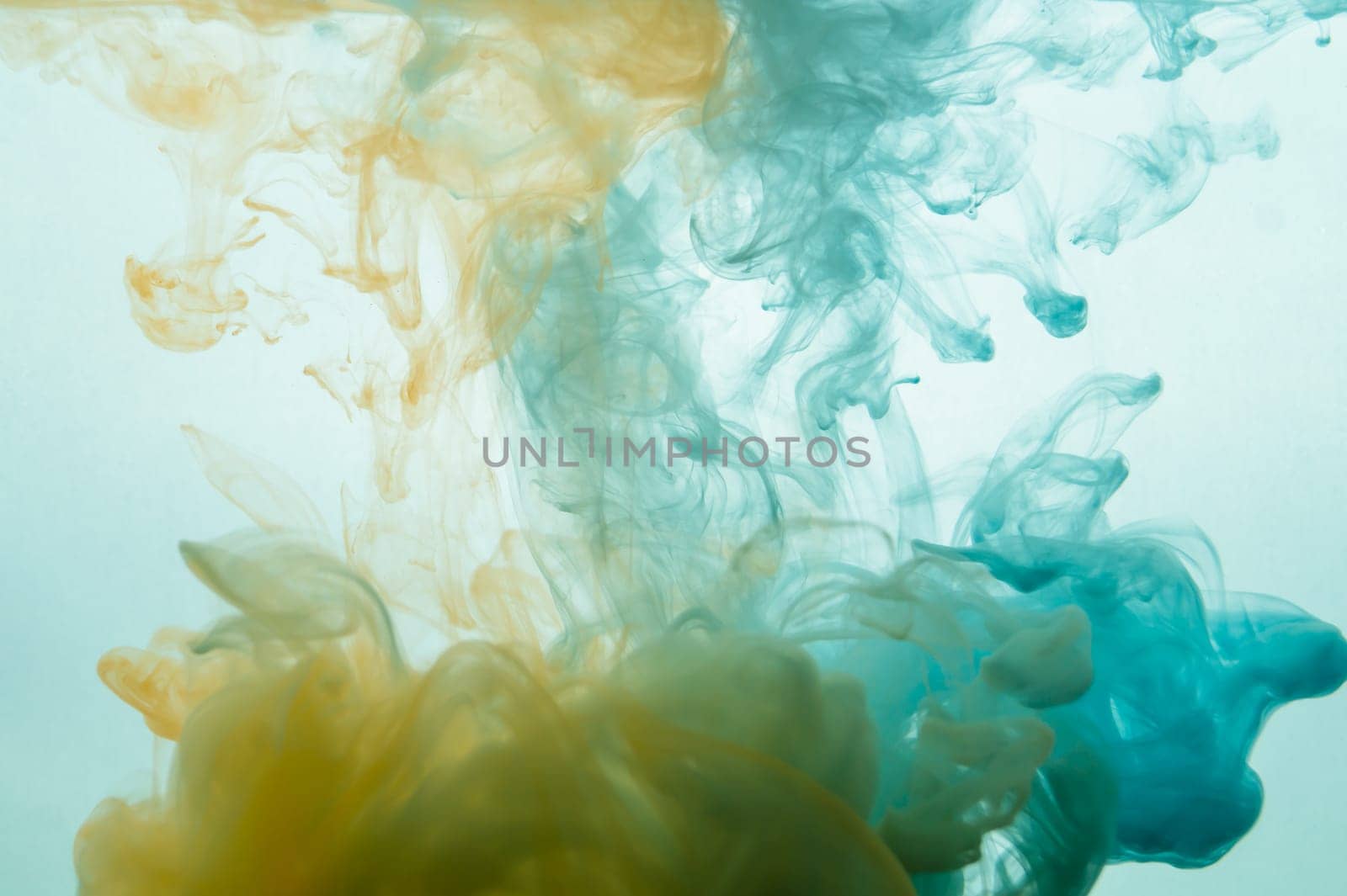 Paint in the water. ink in fluid. abstract background. colorful splashes in liquid. yellow and blue colors