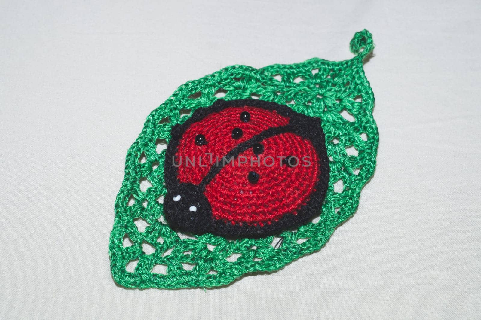 Knitted toy ladybug on a crocheted leaf. handmade pincushion close up