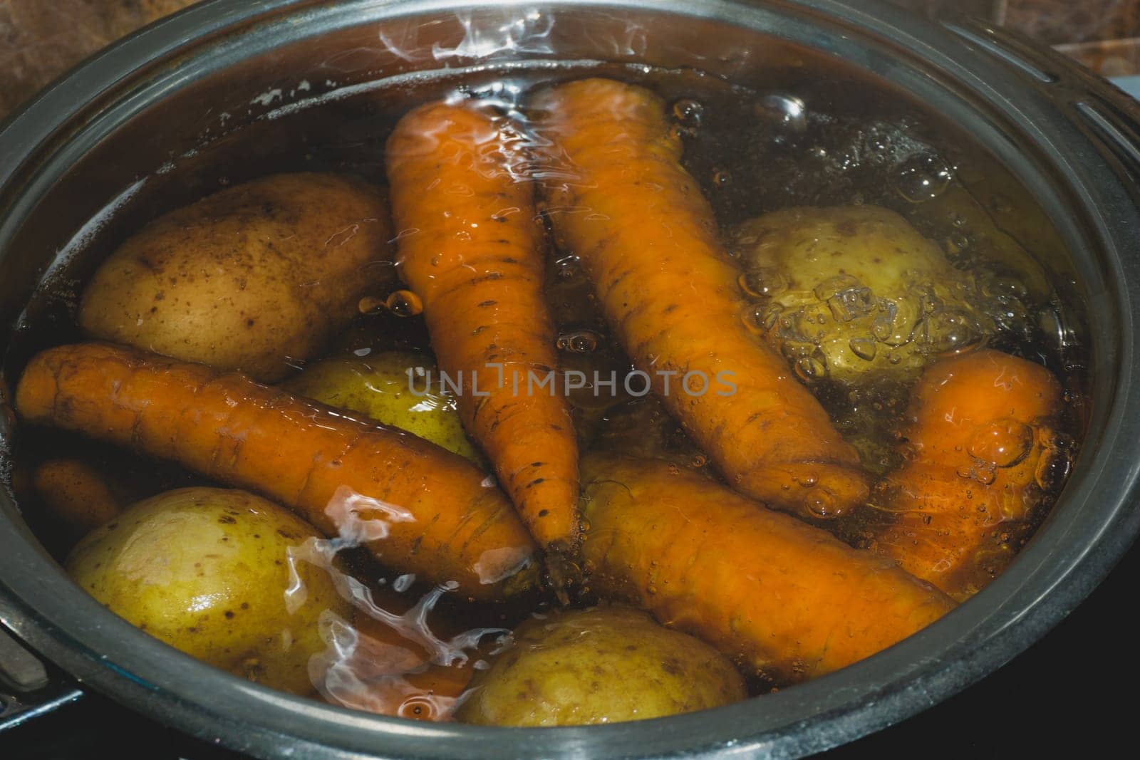 Potatoes and carrots boiling in a pot with hot water. preparing vegetables for salad
