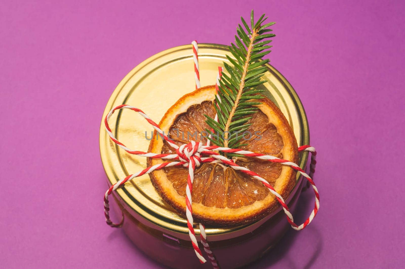 Homemade jam in a decorated jar with orange slice and fir tree twig. handmade Christmas gift