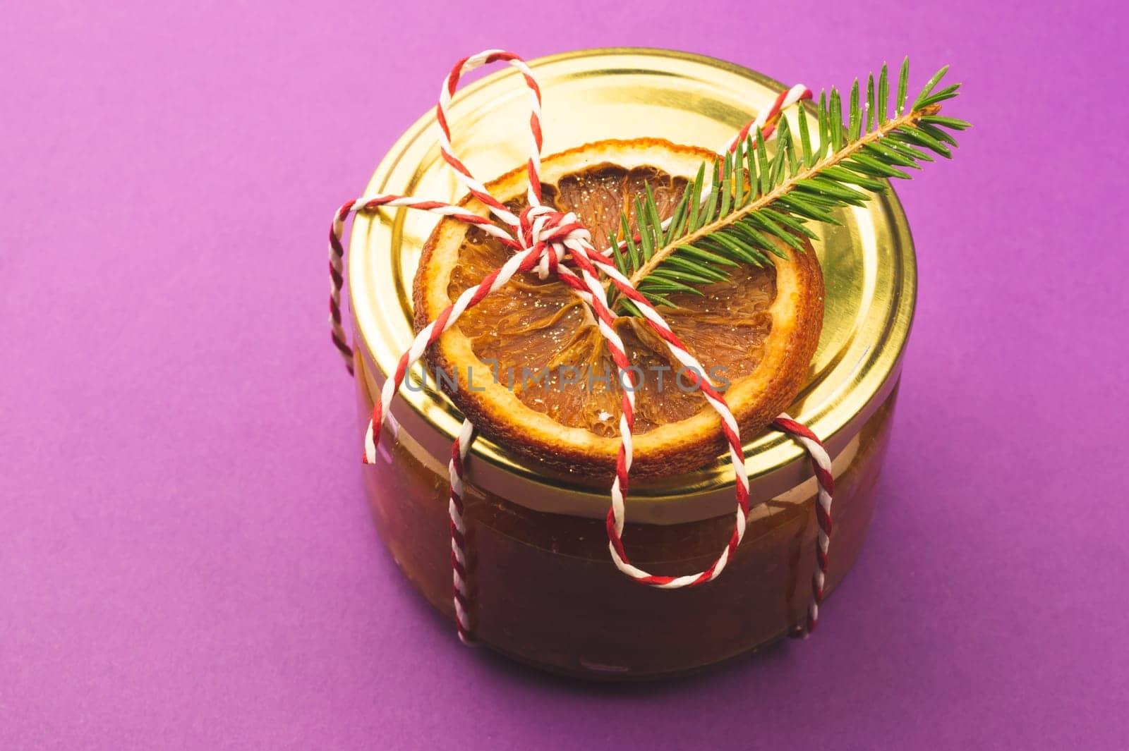 Homemade jam in a decorated jar with orange slice and fir tree twig. handmade Christmas gift