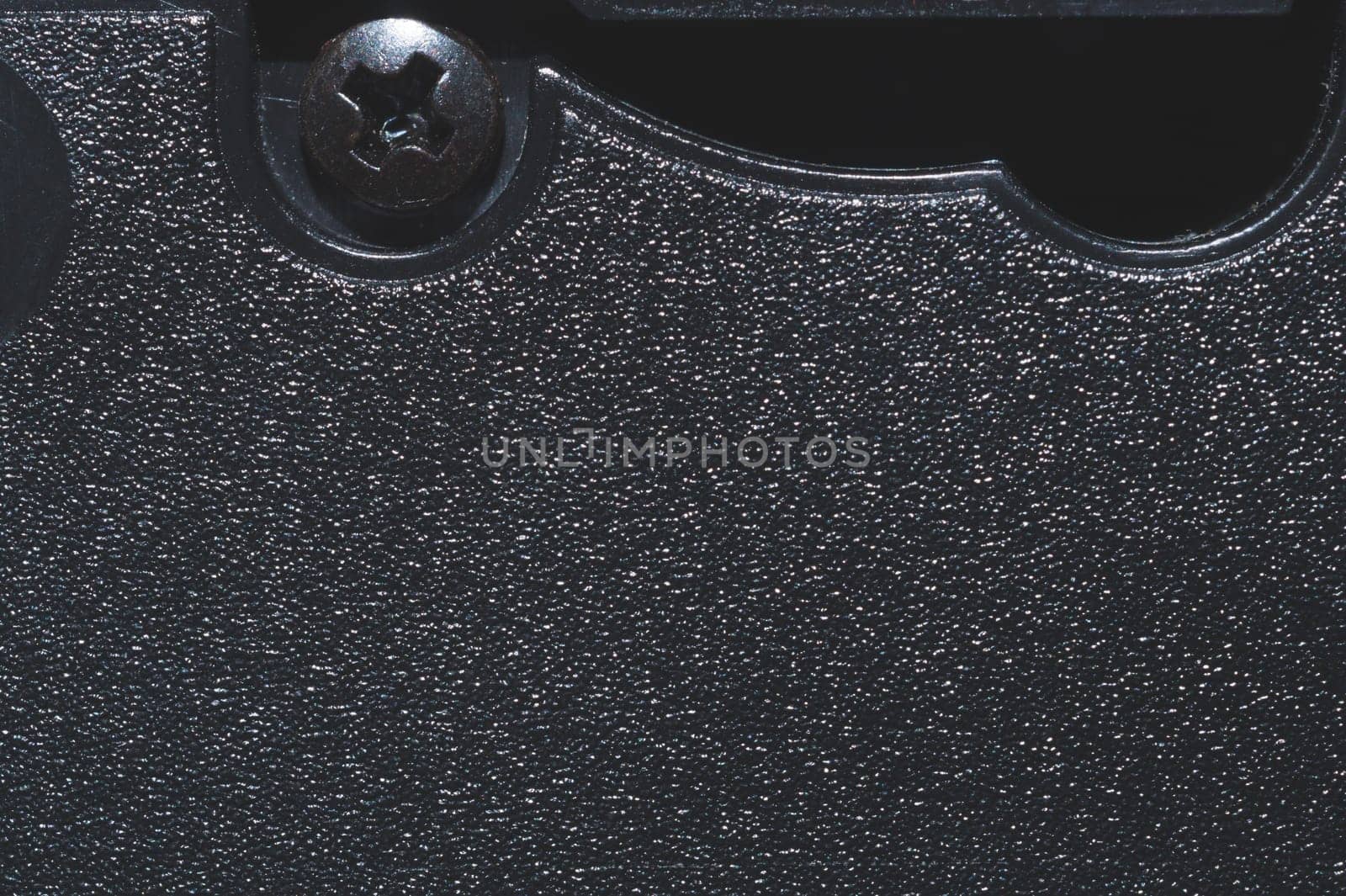 Black plastic surface with screw. detail of plastic cassette close up