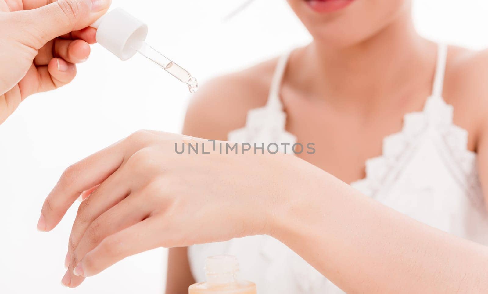 Beautiful woman dropping serum collagen moisturizer into back of the hand to present skin care product isolated on over white background, Vitamin C or E, Beauty and spa concept