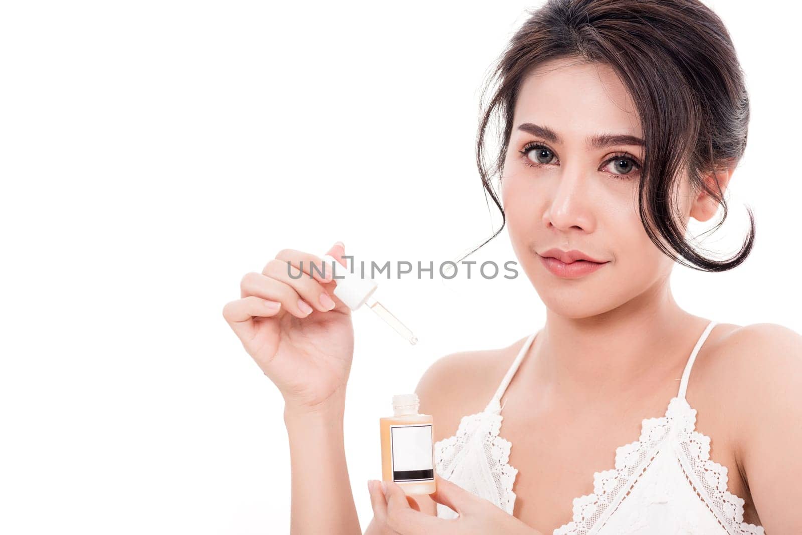 Asian young beautiful woman smiling she's holding bottle serum hair or skin care near face for present product isolated on over white background, Beauty salon concept