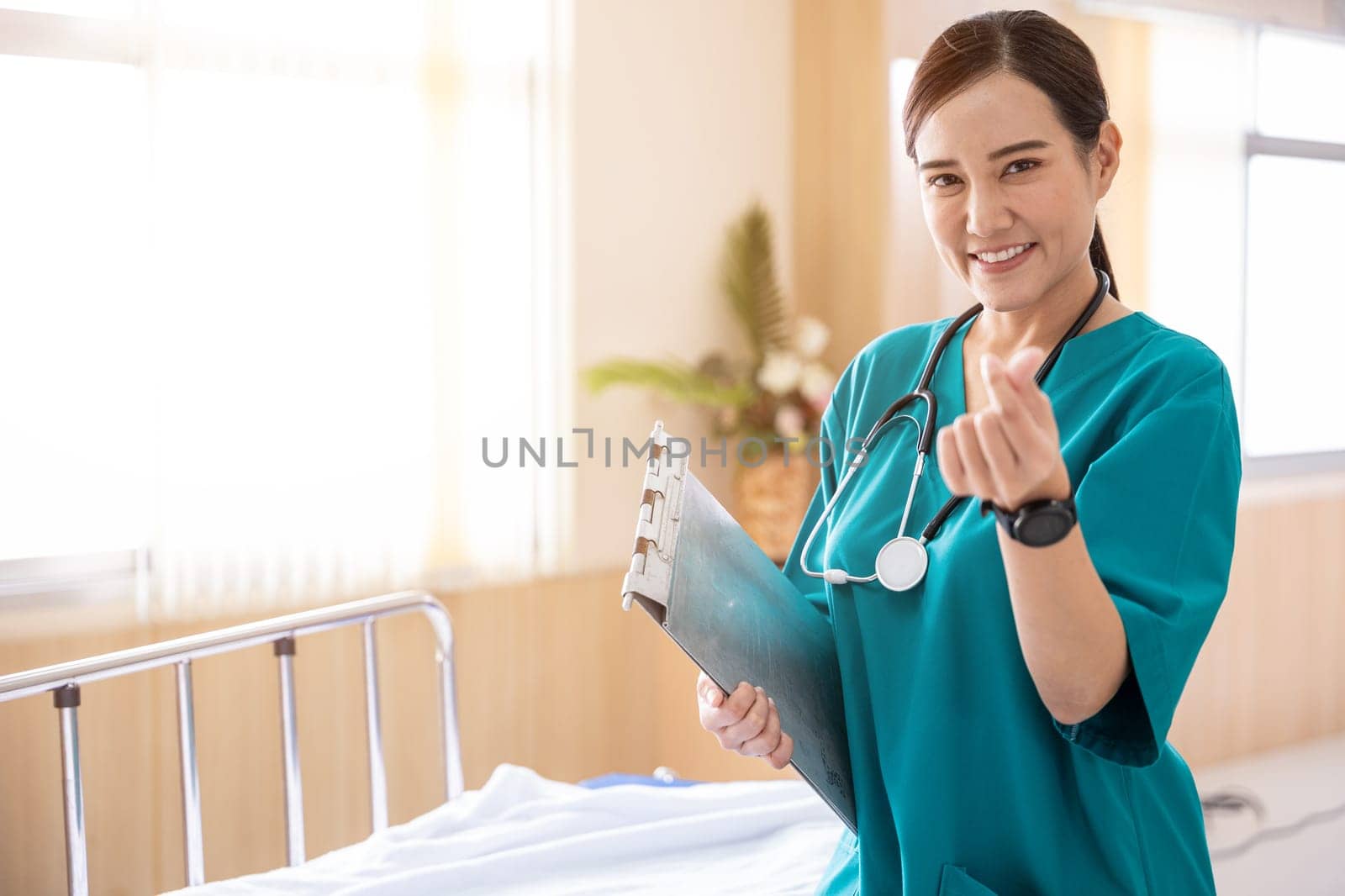 Portrait of a smiling nurse or medical staff make a mini heart hand sign in a hospital, happy woman doctor in uniform holding clipboard, people medical healthcare concept