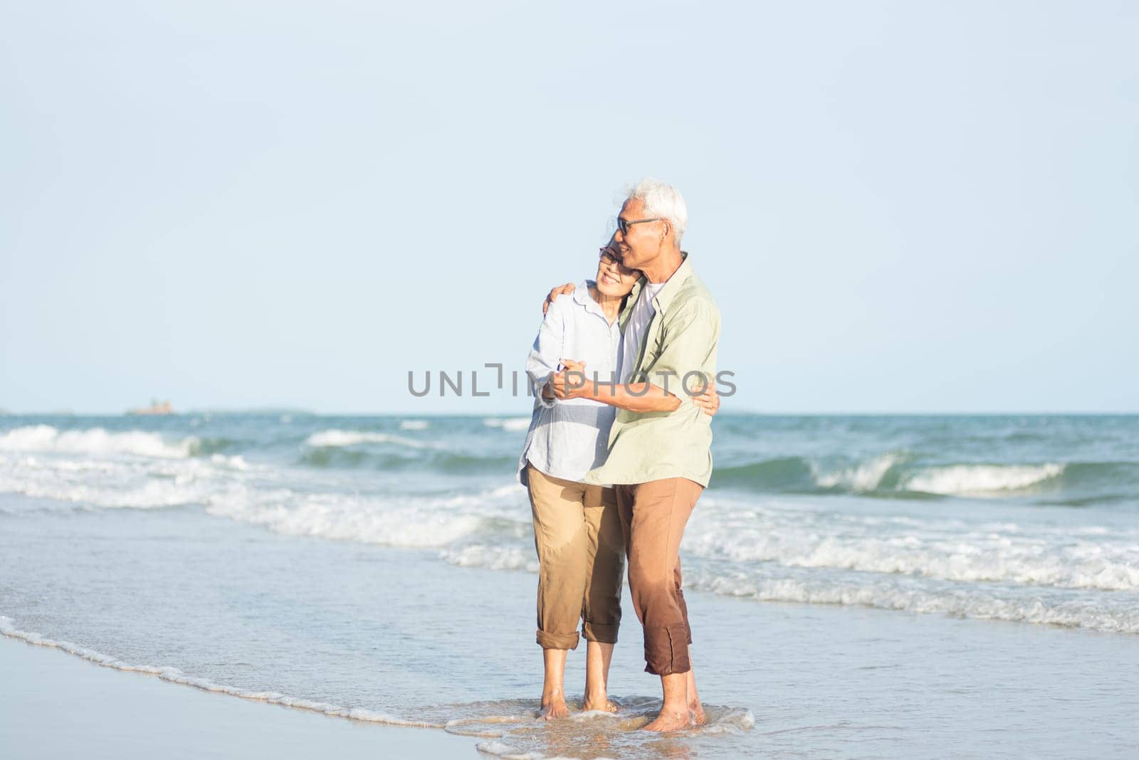 Happy Asian senior man and woman couple smile dancing resting relax on the beach honeymoon family sunny day, Romantic elderly enjoy travel summer vacation, plan life insurance at retirement couple