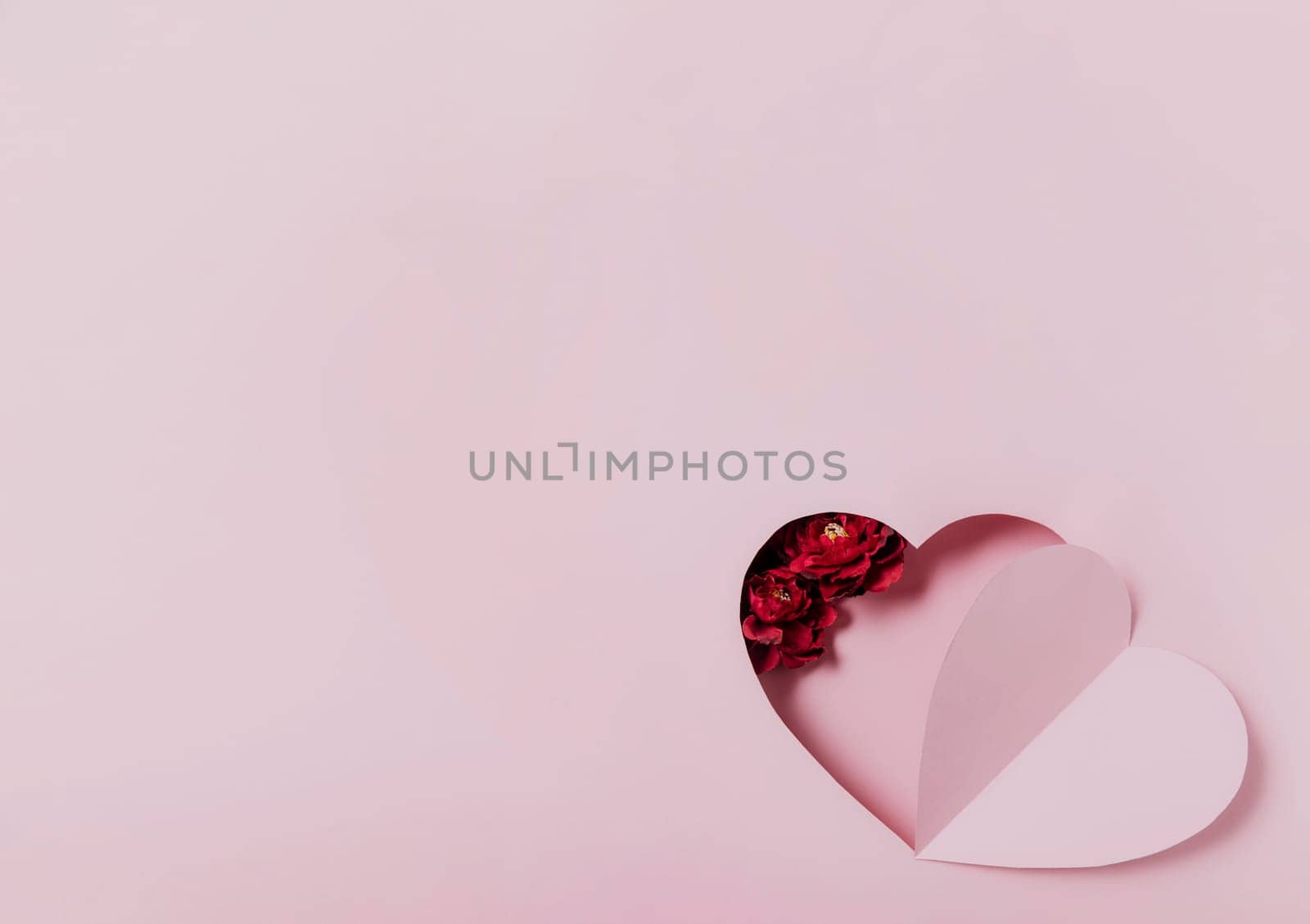 Love message, Saint Valentine Day conceptual flat lay. Top view on cut, curved paper pink heart shape on pink background. Minimal mockup for valentine card, invitation, greeting card. Red rose flower
