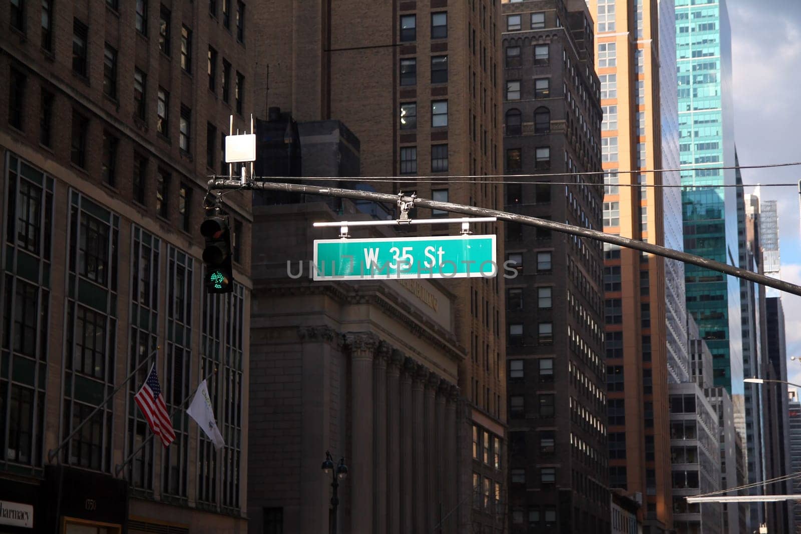 Green big West 35th Street sign hanging on a arch pole in the streets of midtown Manhattan in New York City