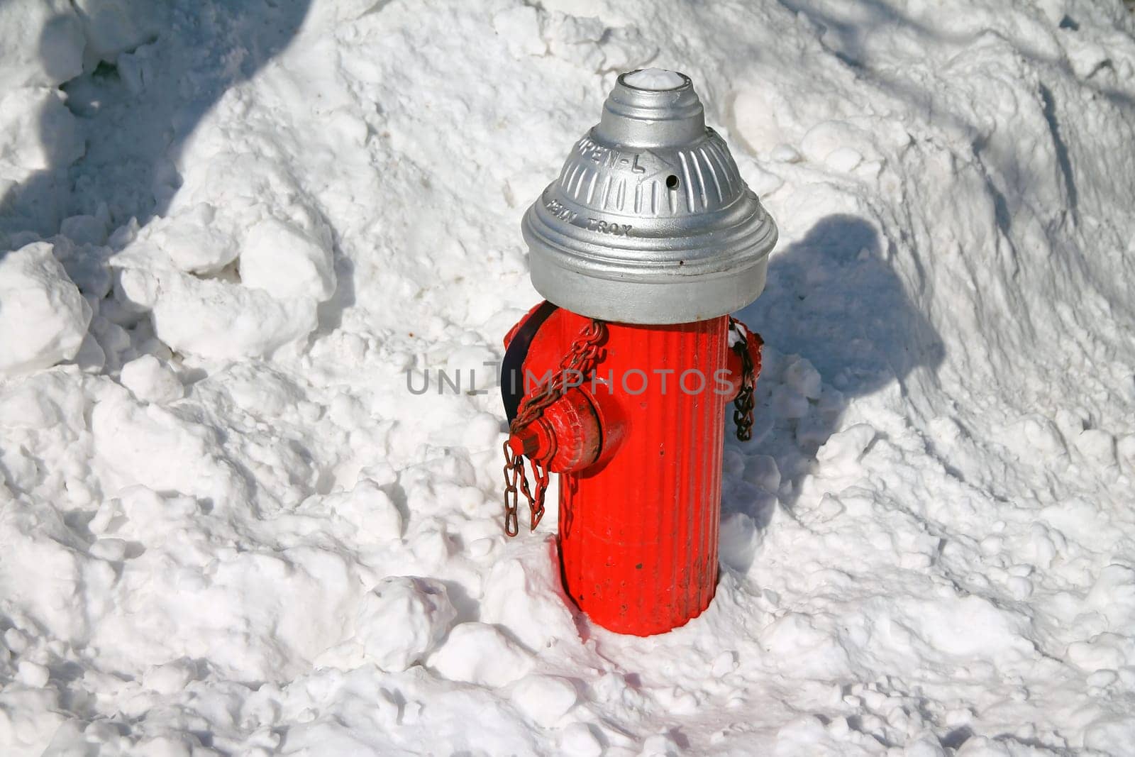 A traditional red and white old hydrant in the white snow A traditional red and white old hydrant with ice and snow on the ground in a winter sunny day