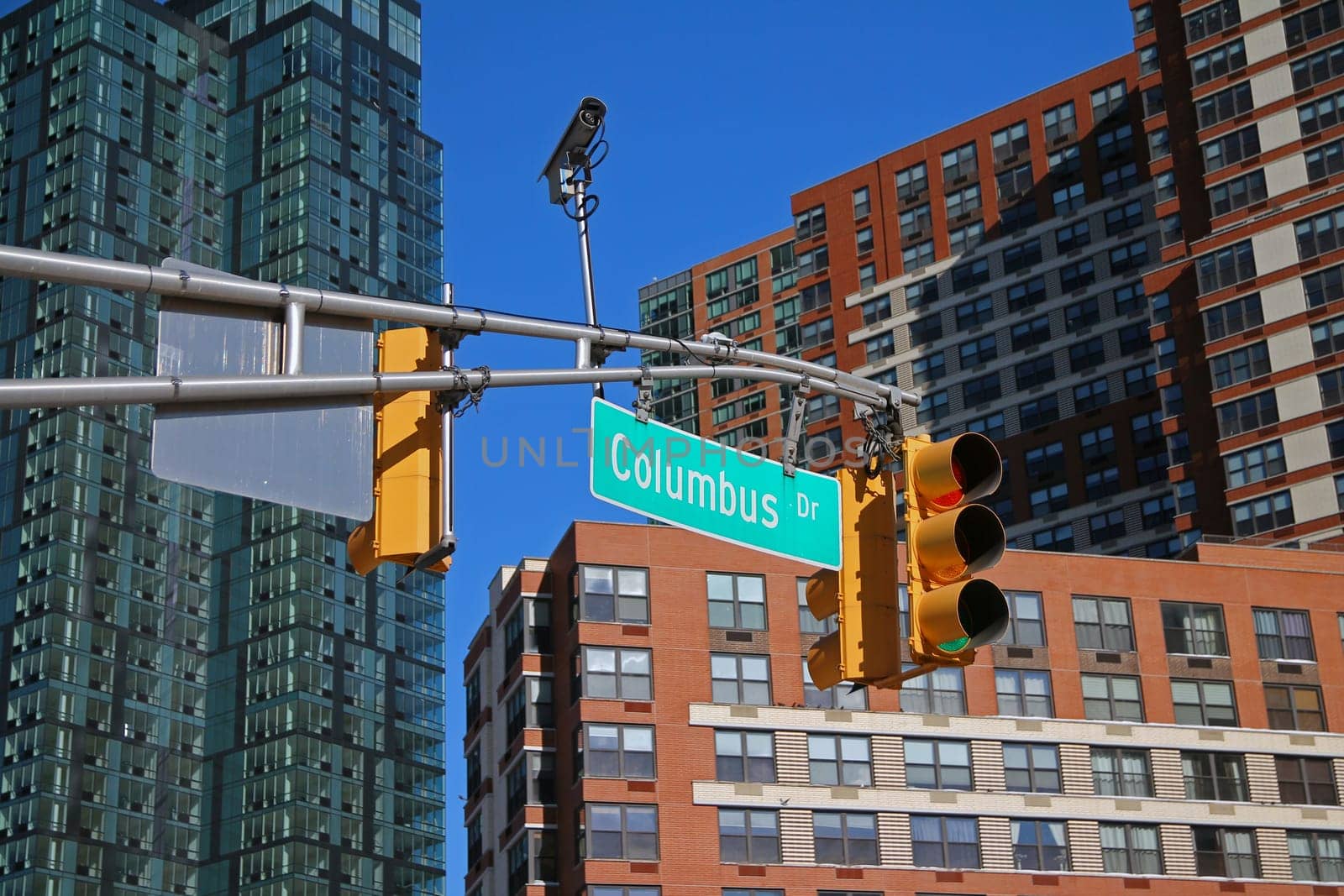 Green big Columbus Drive sign hanging on a arch pole between traffic lights in the streets of downtown Jersey City