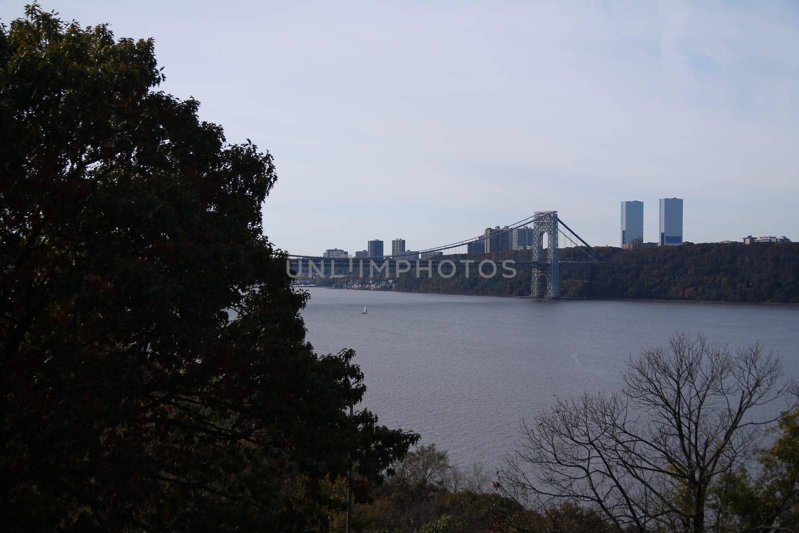 Part of the Washington bridge behind the trees on the Hudson river in New York City